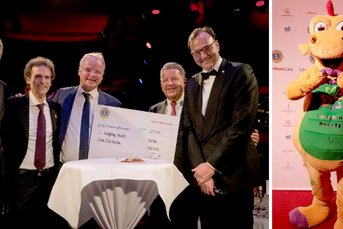 Die Männer lächeln stolz, während sie einen Scheck über 25.000 Euro für die Organisation 'Laughing Hearts' halten.