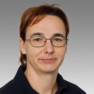 Professionelles Porträt einer Person mit Brille Eine Person mit Brille und kurzen, braunen Haaren blickt direkt in die Kamera, mit einem neutralen Gesichtsausdruck.