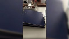 Ein blauer Ordner liegt auf einem Tisch, umgeben von Pizzakartons und Snacks, während eine Person im Hintergrund sitzt.