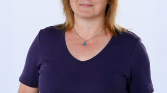 Die Frau trägt ein lila T-Shirt und zeigt stolz ein kleines, blaues Lieferfahrzeug mit dem Logo 'Mercedes'.