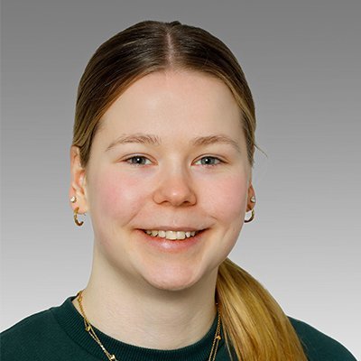 Die Person trägt ein grünes Sweatshirt und hat mehrere Ohrringe, während sie direkt in die Kamera schaut.