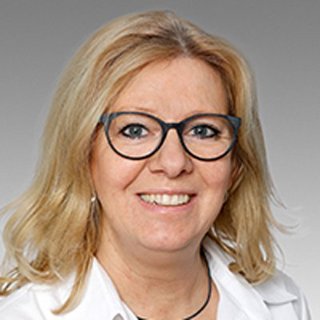 Professionelle Porträtaufnahme einer lächelnden Frau Eine blonde Frau mit Brille lächelt freundlich in die Kamera, trägt ein weißes Hemd und hat eine entspannte Ausstrahlung.