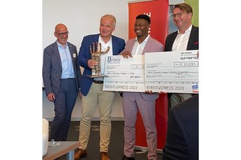 Der Gewinner Mario Zacarias Mungai lächelt, während er einen Preis und einen Scheck über 10.000 Euro präsentiert.