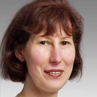 Eine Frau mit schulterlangen, braunen Haaren und einem freundlichen Lächeln, vor einem neutralen Hintergrund.