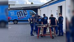 Eine Gruppe von Handwerkern in blauen Arbeitsanzügen versammelt sich um einen Tisch, um an einem Projekt zu arbeiten.