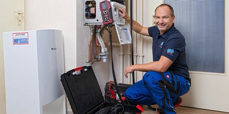 In einem modernen Raum arbeitet ein Techniker an einer Heizungsanlage, um sicherzustellen, dass alles ordnungsgemäß funktioniert.