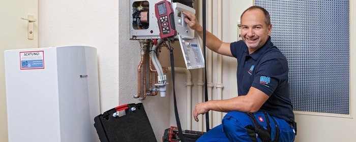 In einem modernen Raum arbeitet ein Techniker an einer Heizungsanlage, um sicherzustellen, dass alles ordnungsgemäß funktioniert.