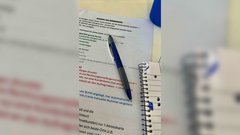 Auf einem Tisch liegen mehrere Dokumente mit bunten Textmarkierungen und einem blauen Kugelschreiber, der darauf zeigt.