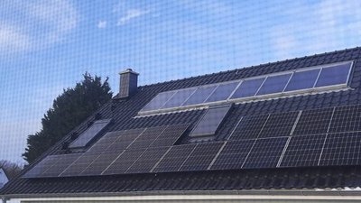 Ein modernes Haus mit einem Dach voller Solarpanels, das unter einem klaren blauen Himmel steht.